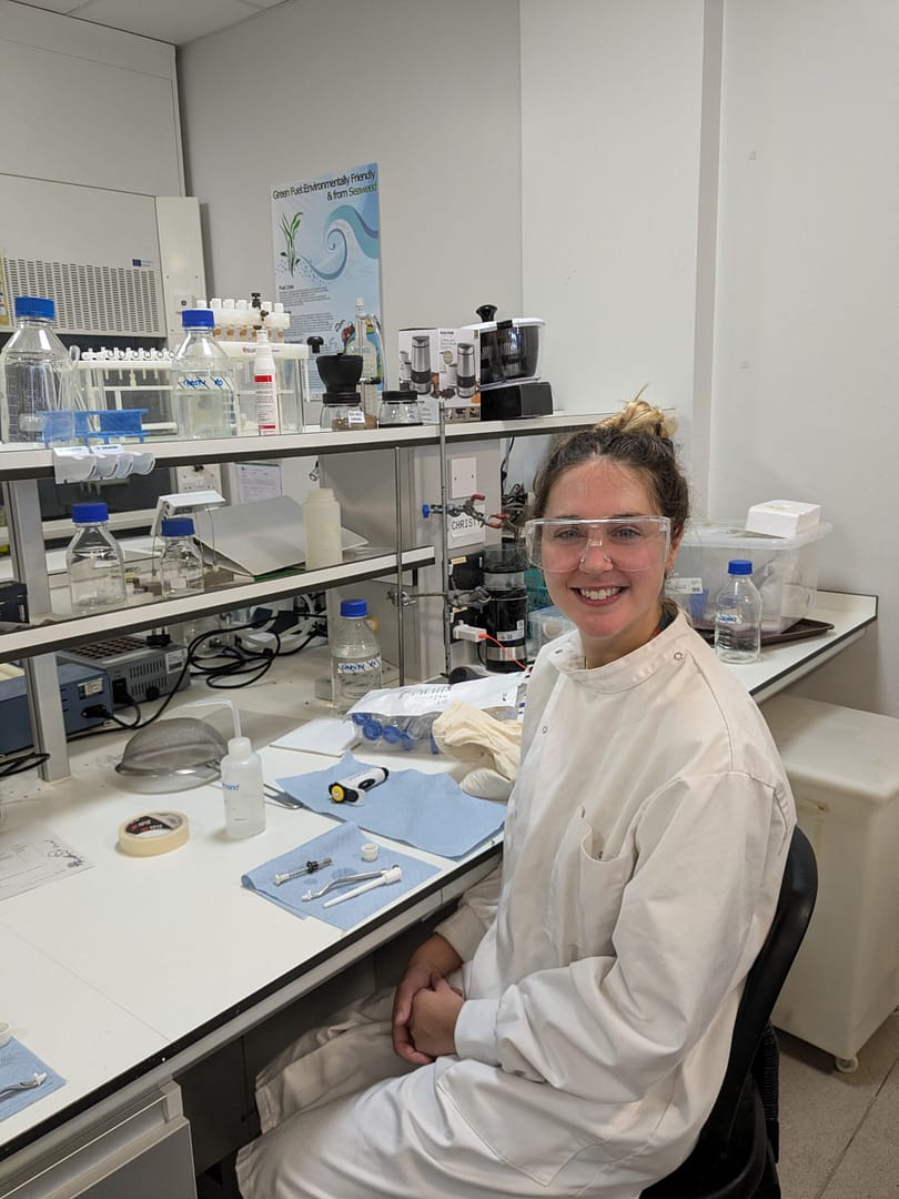 Christy Smith in the lab wearing a lab coat and eye protection